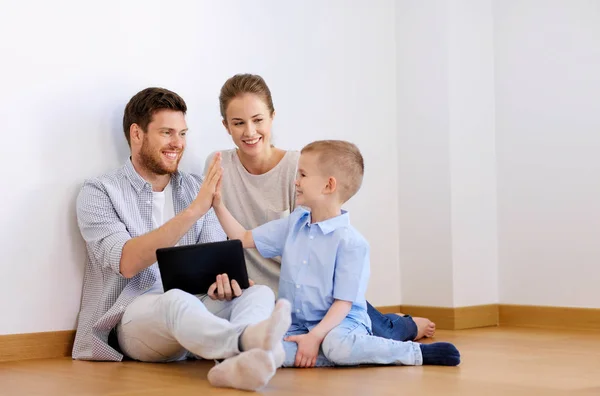 Familia con la PC tableta en el nuevo hogar haciendo alta cinco —  Fotos de Stock