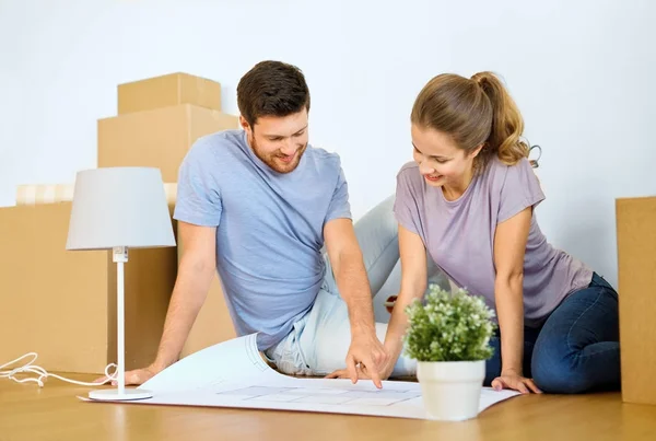 Casal com caixas e plano de mudança para nova casa — Fotografia de Stock