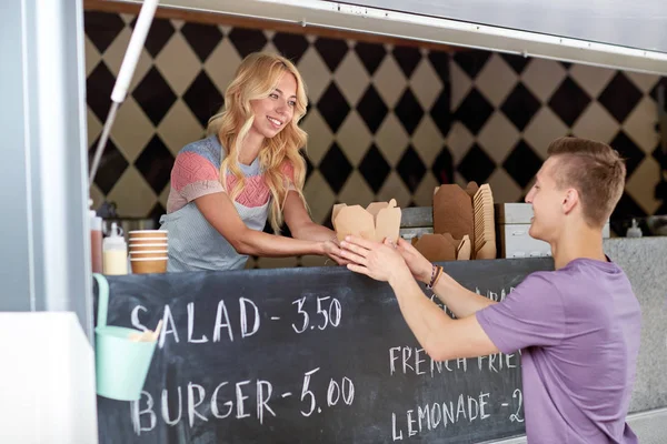 Saleswoman at food truck serving male customer — Stock Photo, Image