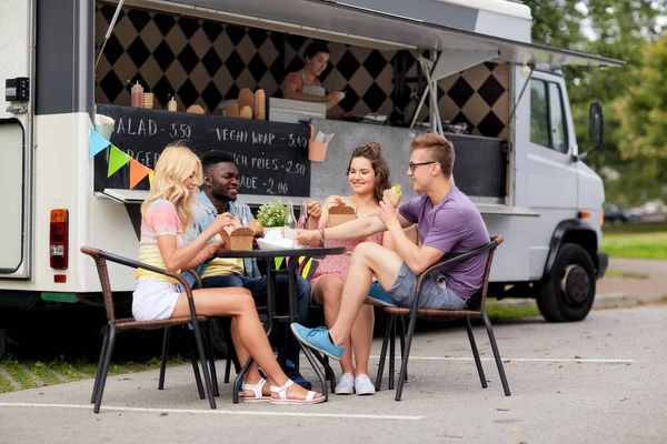 Amici felici con bevande mangiare al camion cibo — Foto Stock