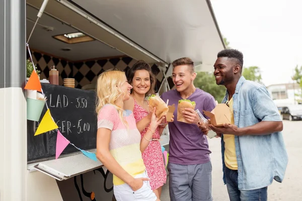 Amis heureux avec des boissons manger au camion de nourriture — Photo