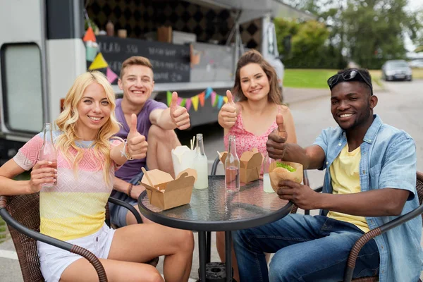 Amis heureux avec des boissons manger au camion de nourriture — Photo