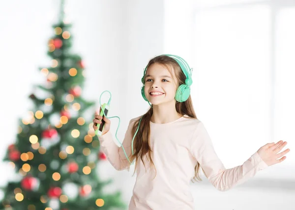 在圣诞节的女孩智能手机和耳机 — 图库照片