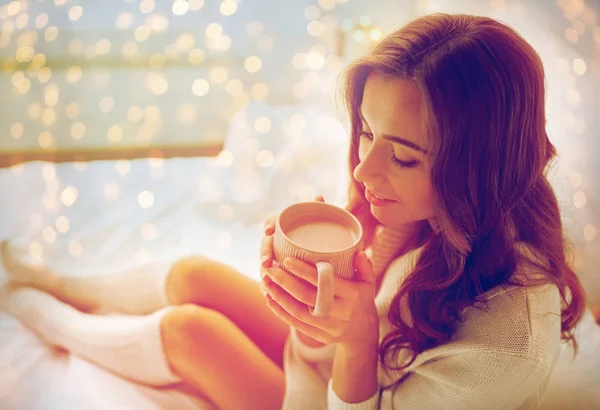 Счастливая женщина с чашкой кофе в постели дома — стоковое фото