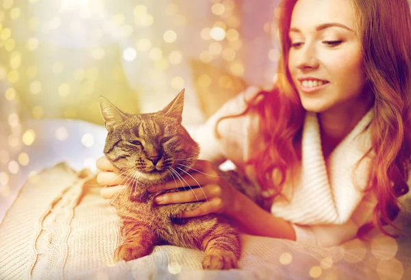Szczęśliwa młoda kobieta z kotem, leżąc w łóżku w domu — Zdjęcie stockowe