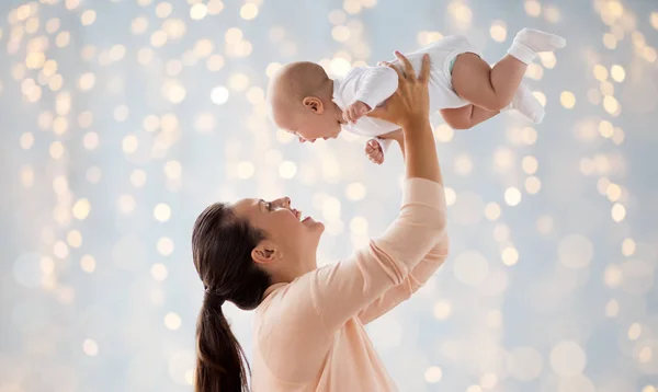 Feliz madre jugando con poco bebé sobre luces — Foto de Stock