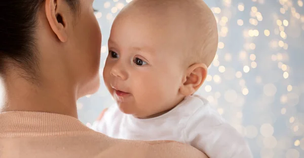 Primer plano del bebé feliz con la madre sobre las luces —  Fotos de Stock