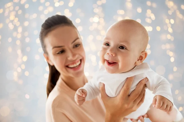 Lycklig mamma leker med lilla bebis över lampor — Stockfoto
