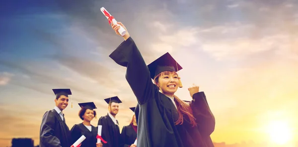 Estudiantes felices en morteros con diplomas —  Fotos de Stock