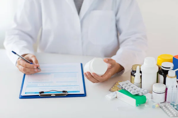 Doctor with medicines and clipboard at hospital — Stock Photo, Image