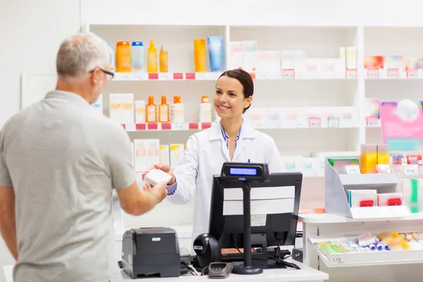 Apothecary selling drug to senior man at pharmacy — Stock Photo, Image