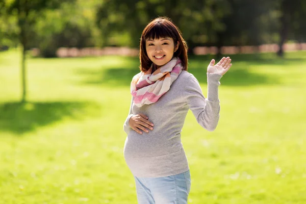 Feliz grávida asiático mulher acenando mão no parque — Fotografia de Stock