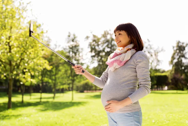 Happy pregnant asian woman taking selfie at park — Stock Photo, Image