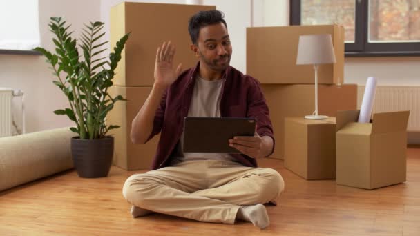 Человек с планшетным компьютером и коробками переезжает в новый дом — стоковое видео