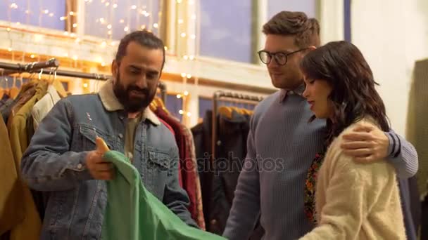Amigos eligiendo ropa en la tienda de ropa vintage — Vídeo de stock