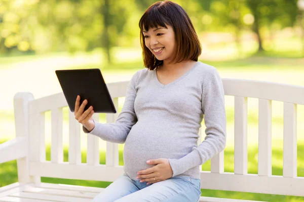 Happy pregnant asian woman with tablet pc at park — Stock Photo, Image