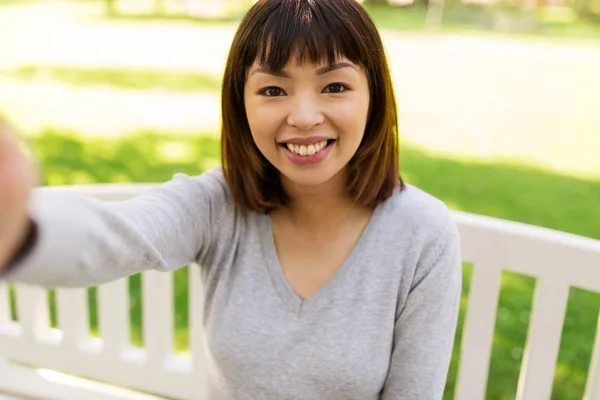 Felice sorridente donna asiatica prendendo selfie al parco — Foto Stock