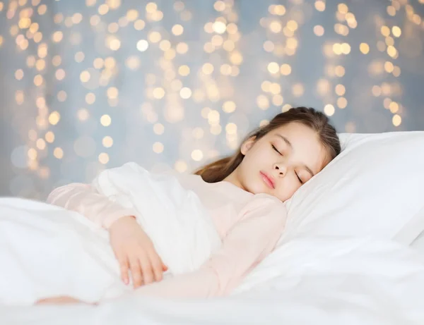 Chica durmiendo en la cama durante las vacaciones luces —  Fotos de Stock