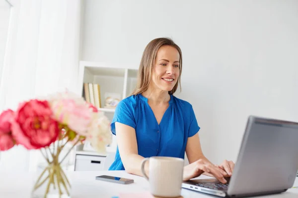 Glückliche Frau mit Laptop, die zu Hause oder im Büro arbeitet — Stockfoto