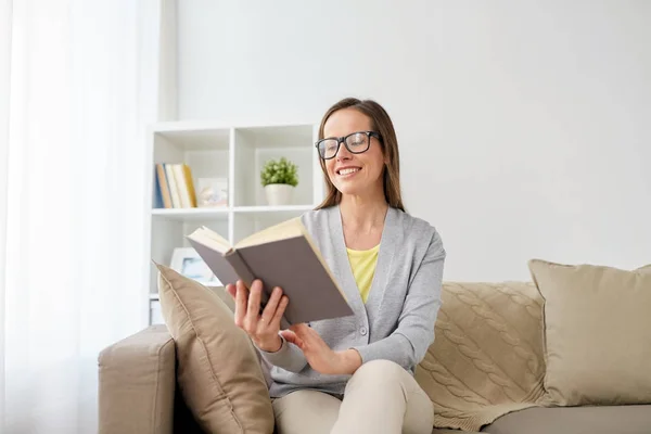 Glückliche Frau mit Brille liest Buch zu Hause — Stockfoto