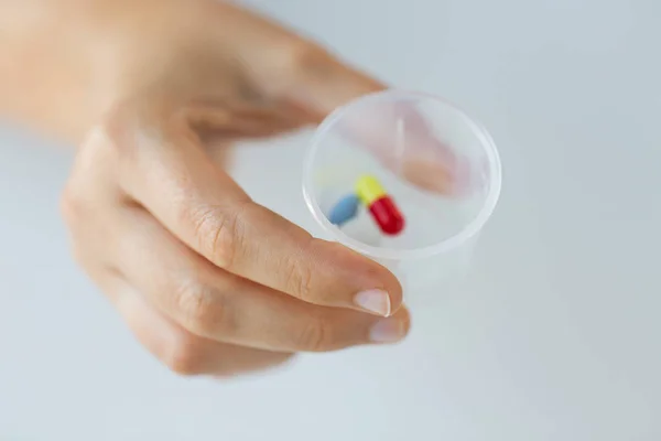 Primer plano de la mano femenina con pastillas en la taza de la medicina —  Fotos de Stock