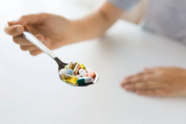 Primer plano de la mano femenina sosteniendo cuchara con pastillas — Foto de Stock