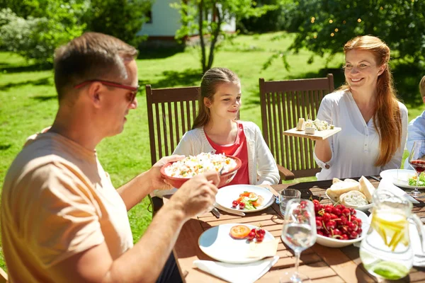 Счастливая семья с ужином или вечеринкой в летнем саду — стоковое фото