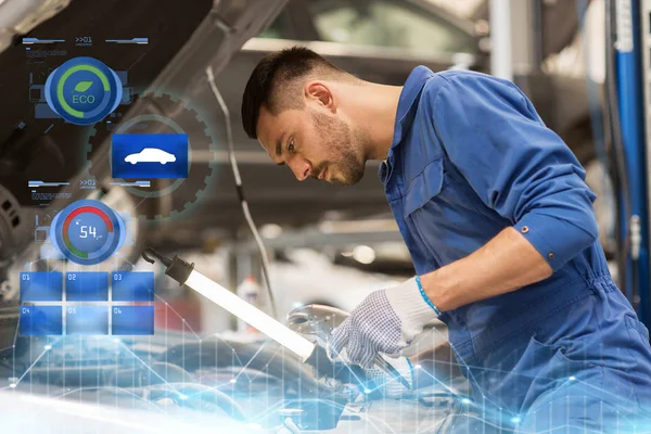 Mechanic man with lamp repairing car at workshop — Stock Photo, Image