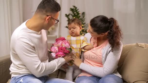 Familia feliz con la niña y las flores en casa — Vídeo de stock