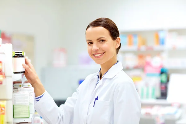 Boticario femenino feliz con la droga en la farmacia —  Fotos de Stock