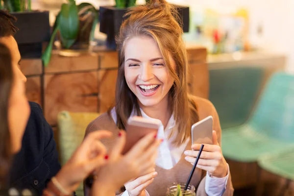 Vrouw met smartphone en vrienden op restaurant — Stockfoto