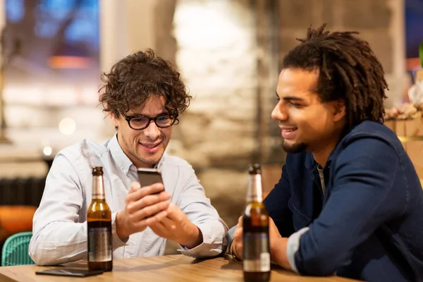 Homens com smartphone bebendo cerveja no bar ou pub — Fotografia de Stock
