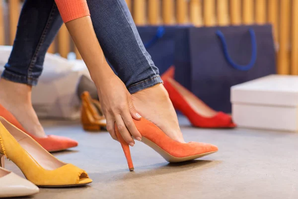 Mujer joven probando zapatos de tacón alto en la tienda —  Fotos de Stock