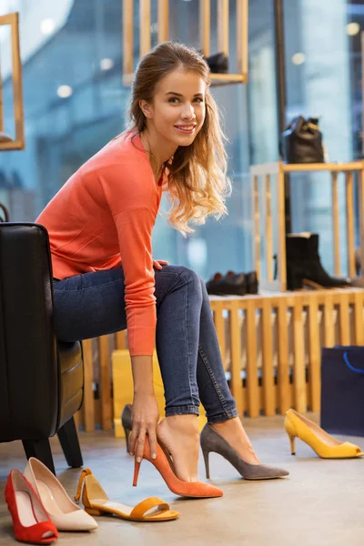 店で高いヒールの靴をしようとしている若い女性 — ストック写真