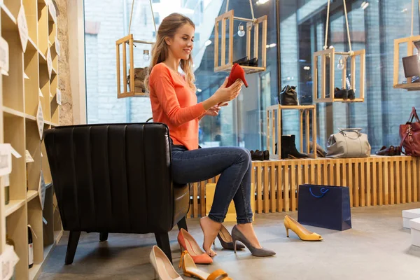 Mujer joven probando zapatos de tacón alto en la tienda —  Fotos de Stock