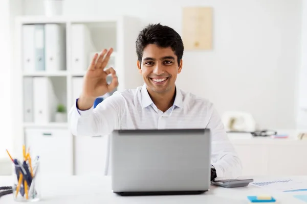 Businessman with laptop showing ok sign at office — Stock Photo, Image