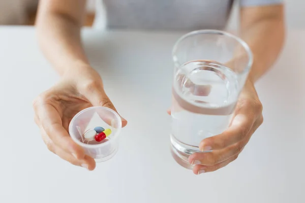 Primer plano de las manos con pastillas y vaso de agua — Foto de Stock