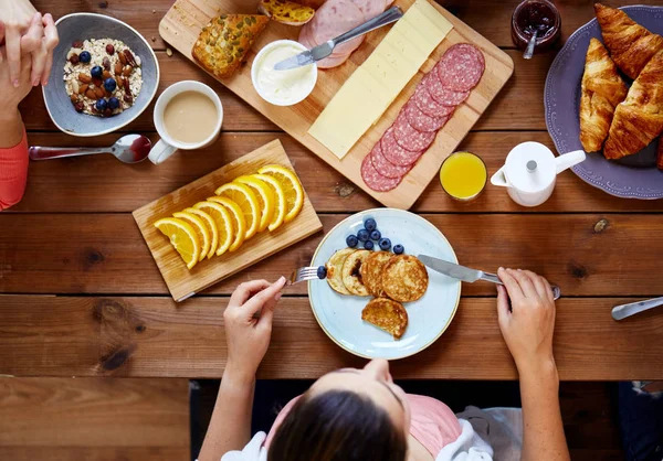 Mujer con comida en la mesa comiendo panqueques — Foto de Stock