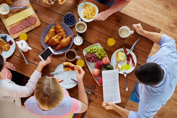 Personas con smartphones comiendo comida en la mesa — Foto de Stock
