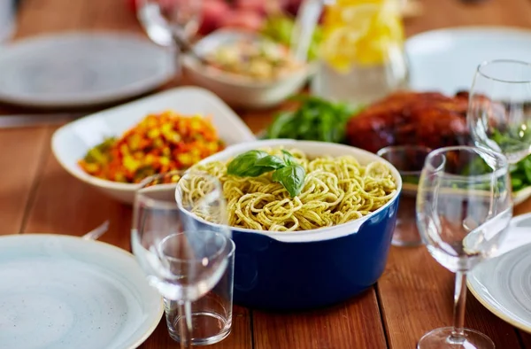 Macarrão com manjericão na tigela e outros alimentos na mesa — Fotografia de Stock