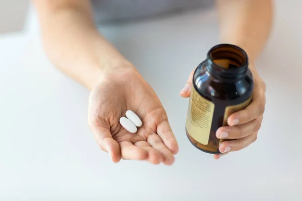 Perto de mãos segurando pílulas de medicina e frasco — Fotografia de Stock