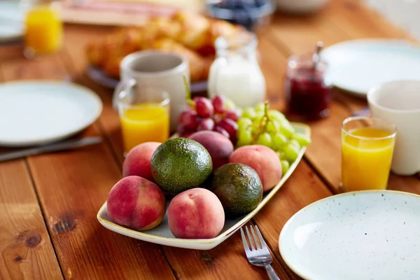 Fruits, jus et autres aliments sur la table au petit déjeuner — Photo