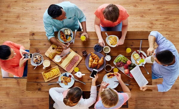 Personnes avec des smartphones manger de la nourriture à table — Photo