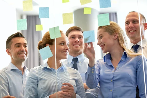 Business team at glass wall with sticky notes — Stock Photo, Image