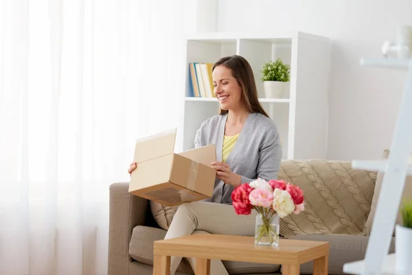 Χαμογελαστό γυναίκα άνοιγμα δέματος κουτί στο σπίτι — Φωτογραφία Αρχείου