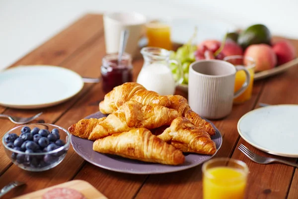 Plate of croissants on wooden table at breakfast — Stock Photo, Image