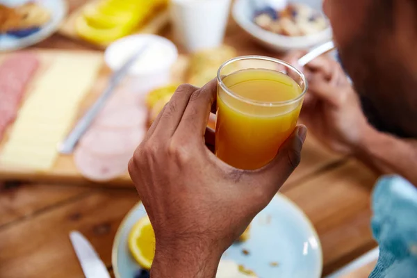 Крупним планом чоловіча рука зі склянкою апельсинового соку — стокове фото