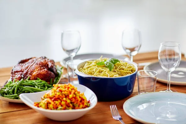 Pasta con albahaca en un tazón y otros alimentos en la mesa —  Fotos de Stock