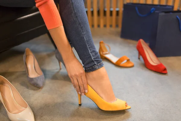 Young woman trying high-heeled shoes at store — Stock Photo, Image