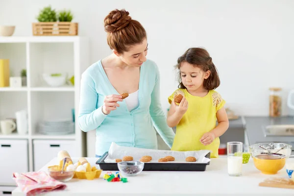 Feliz madre e hija comiendo galletas en casa —  Fotos de Stock